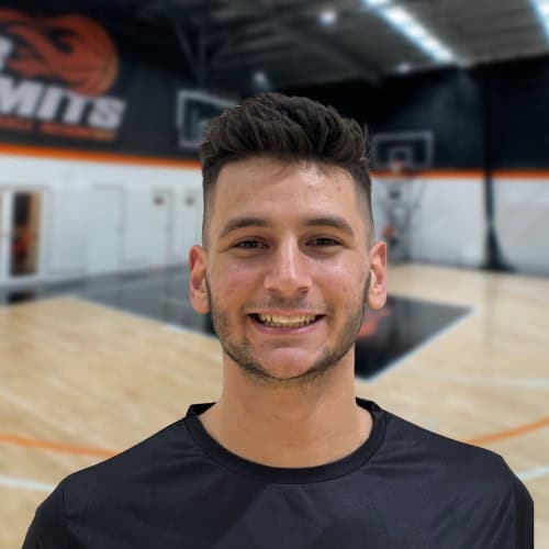 Young man smiling on basketball court at No Limits Basketball training session.