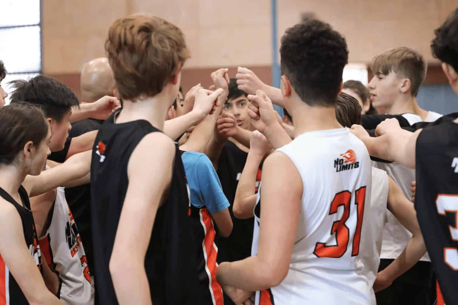 Youth basketball team huddle, No Limits Basketball, team spirit, training, young athletes, sportsmanship, active lifestyle.