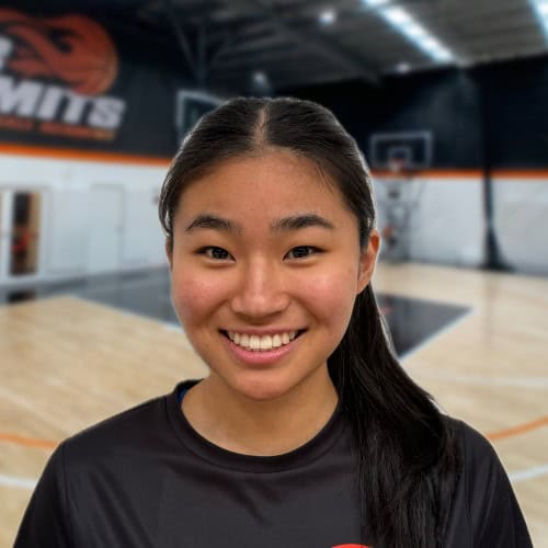 Dynamic female basketball player smiling on indoor court at No Limits Basketball.