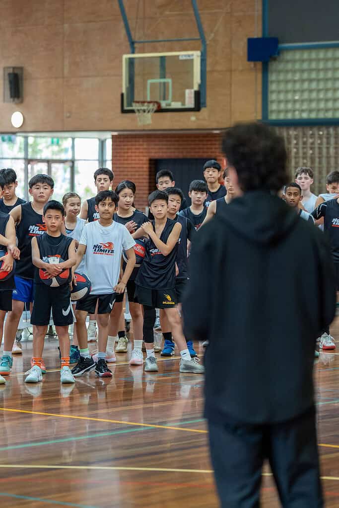 Young basketball players listening to coach in indoor gym.