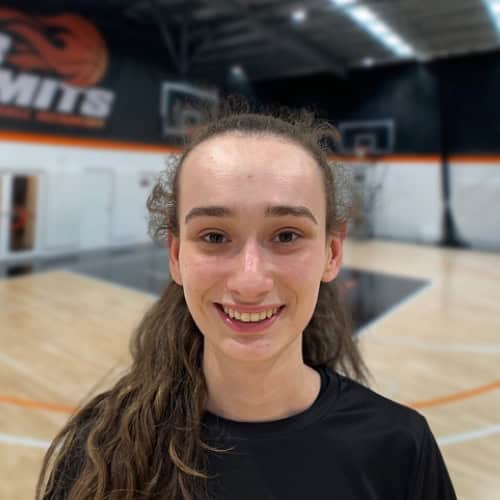 Young female basketball player smiling in indoor court.