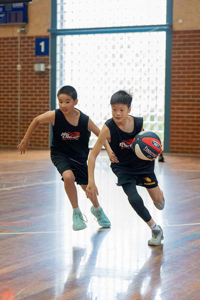Young boys playing basketball indoors during training session.