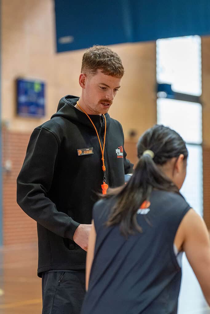 Basketball coach giving instructions to players during training.