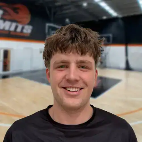 Young male basketball player smiling in indoor court at No Limits Basketball.