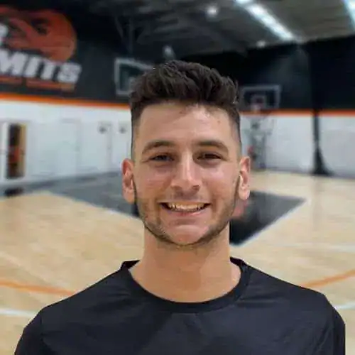 Young male basketball player smiling in indoor court at No Limits Basketball.
