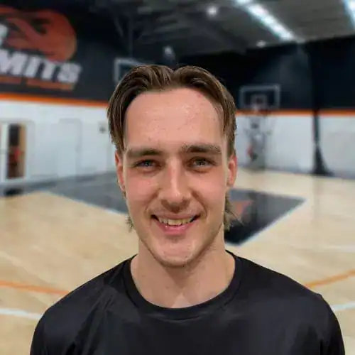Young male basketball player smiling in indoor court at No Limits Basketball.