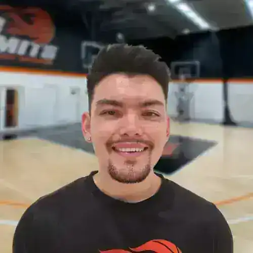 Young male basketball player smiling in indoor court.
